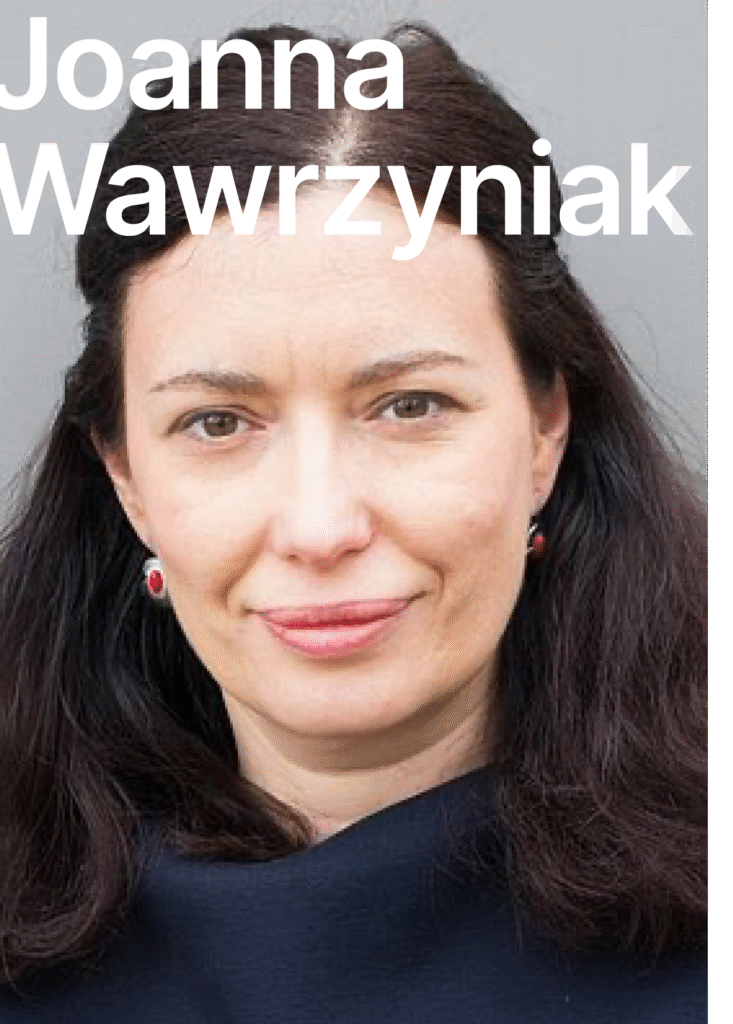 Joanna Wawrzyniak. There is a picture of a smiling woman. She had shoulder long dark hair, she is wearing red earrings and smiling friendly. She is wearing a blue blouse.