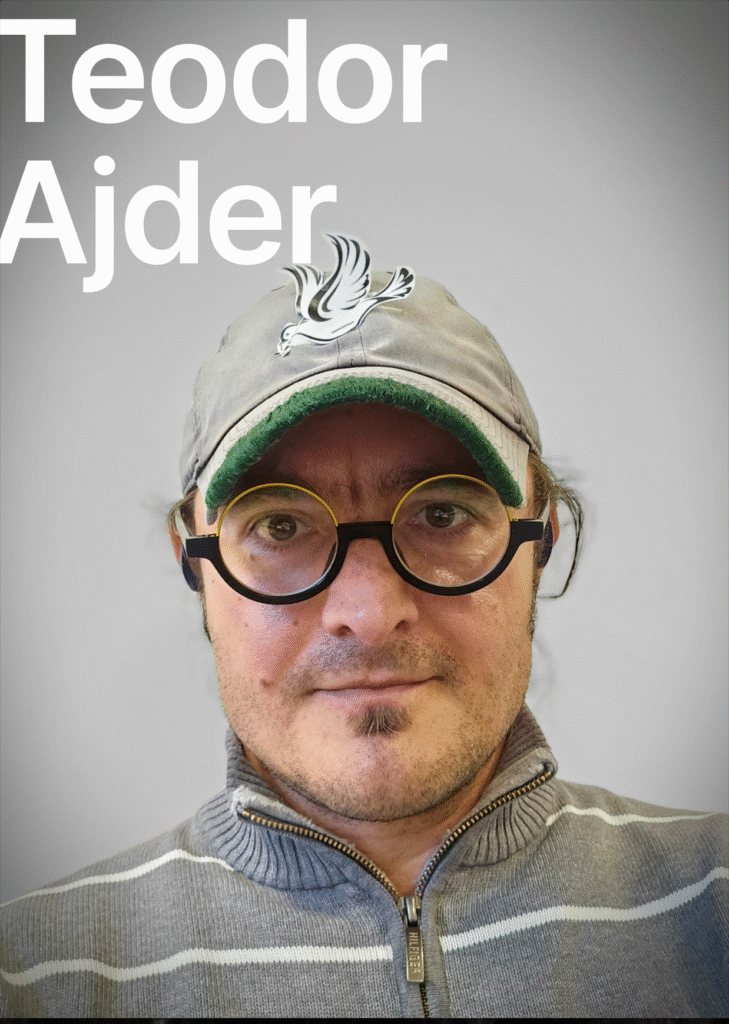 On the grey background is the text Teodor Ajder. The man is looking at the camera. He is wearing a grey cap with a white image of the pigeon on it. He is wearing big glasses with a black frame. He has a small beard. he is wearing a grey pullover.