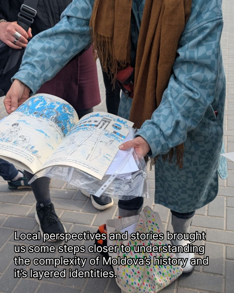 In teh picture there is a person in a blue long coat holding a book in the hands. The book has black and blue drawings and a text. The person also wears a brown scarf. There is a text in the background: local perspectives and stories brought us some steps closer to understanding the complexity of Moldova's history and its layered identities.